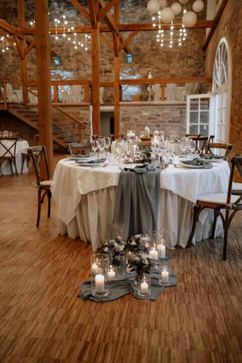 Eleganter Hochzeitsbankettsaal mit rustikalem Ambiente, geschmückten Tischen und funkelnden Lichterketten