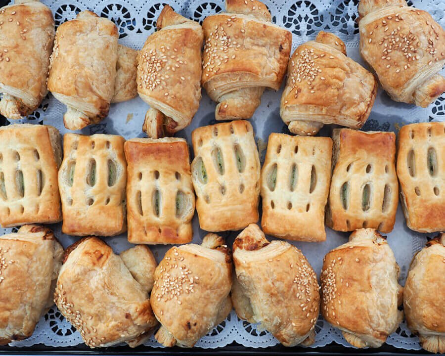 Frische, goldbraune Blätterteiggebäckstücke mit verschiedenen Füllungen und Sesamsamen