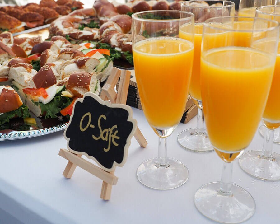 Gläser mit Orangensaft und belegte Bretzeln auf einem Buffet für einen mobilen Sektempfang bei einer Hochzeit