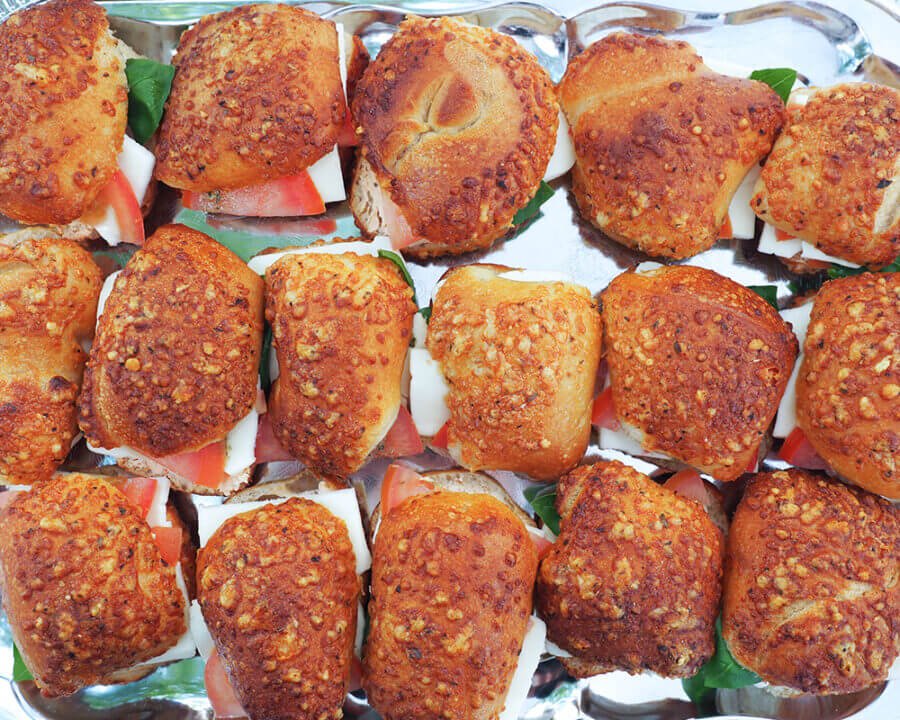 Frisch zubereitete Brötchen mit Tomate und Käse auf einem Tablett für mobilen Sektempfang