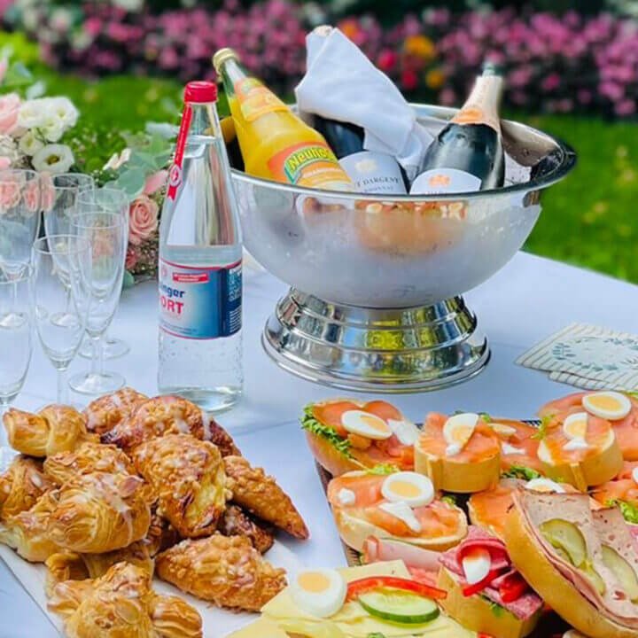 Mobiler Sektempfang mit Sekt, Orangensaft, Gebäck und Canapés auf einem Tisch im Freien